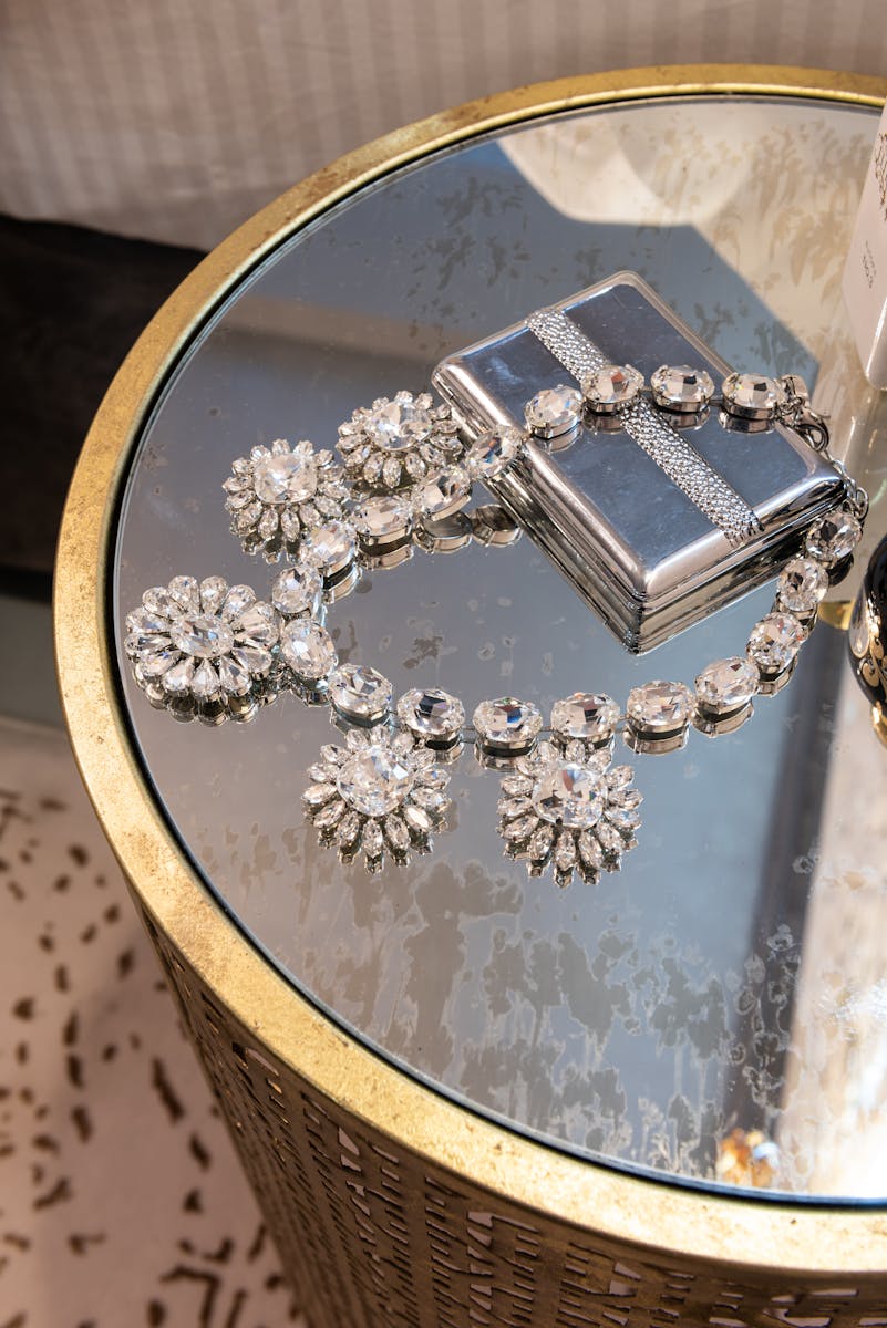 From above of silver necklace with floral ornament and diamonds on metal box on table in house room, home